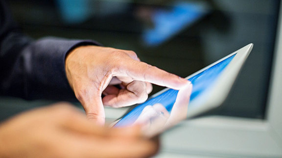 A close-up of a person's hand touching a tablet