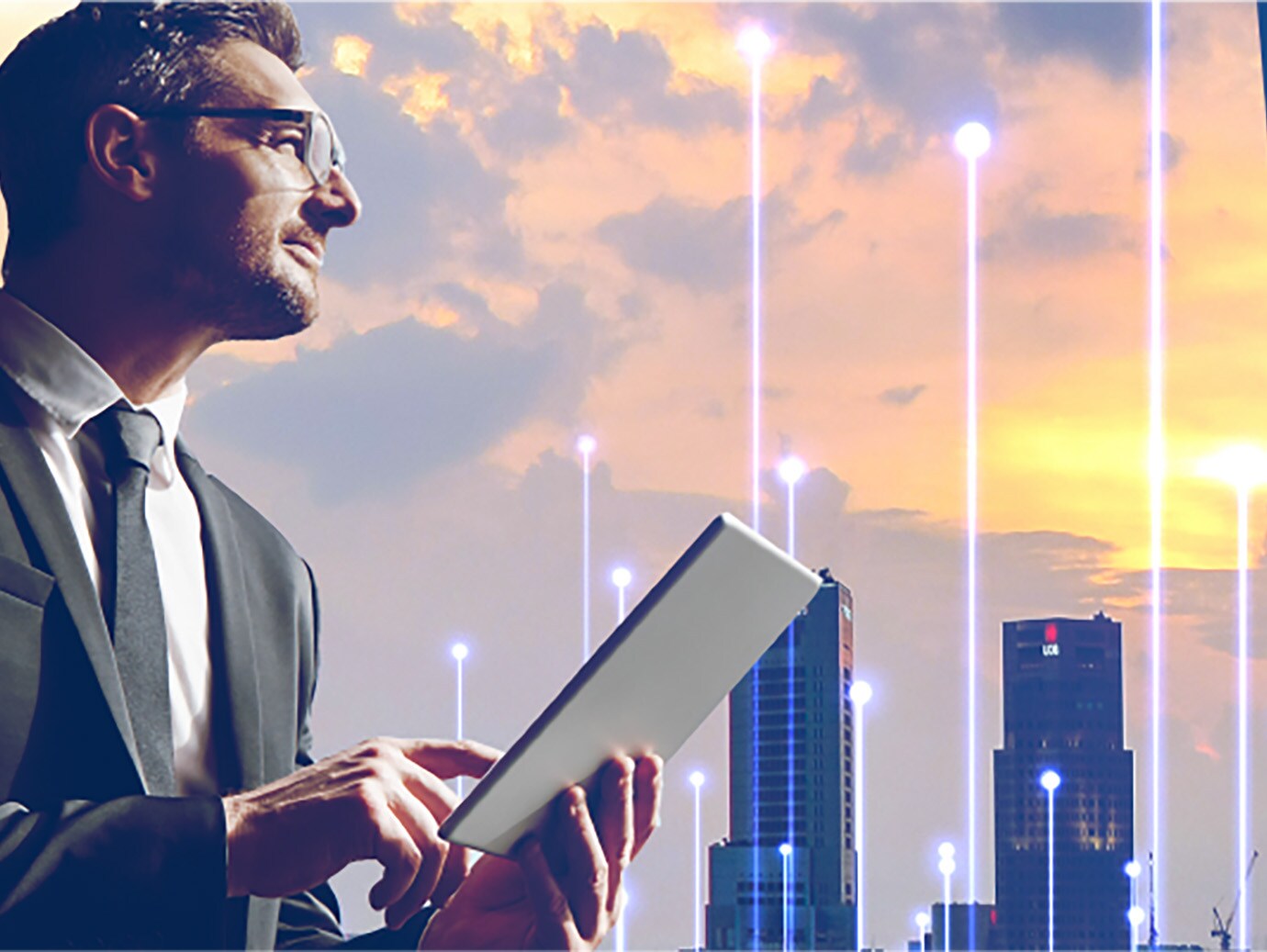 A male employee using a tablet by a window overlooking the cityscape